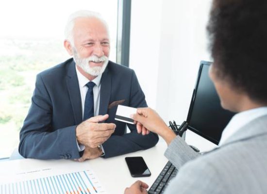 Businesswoman giving credit card to businessman at bank